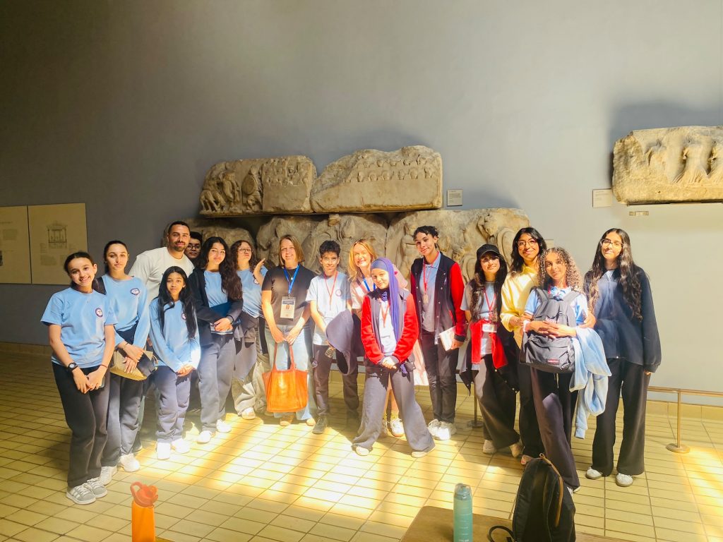 Students from Alexander Flemming School in Casablanca stand in front of an ancient Romanian wall structure at the British Museum with Albert International Guides, Jenny and Christa.